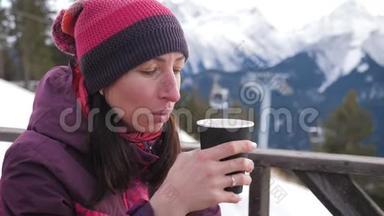 女人在山上的乡村木制露台上喝着温<strong>暖</strong>的<strong>茶</strong>。 女孩正在欣赏雪山的全景